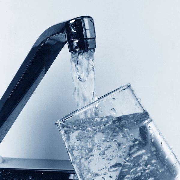 Water pouring from faucet into cup - photo by EPA