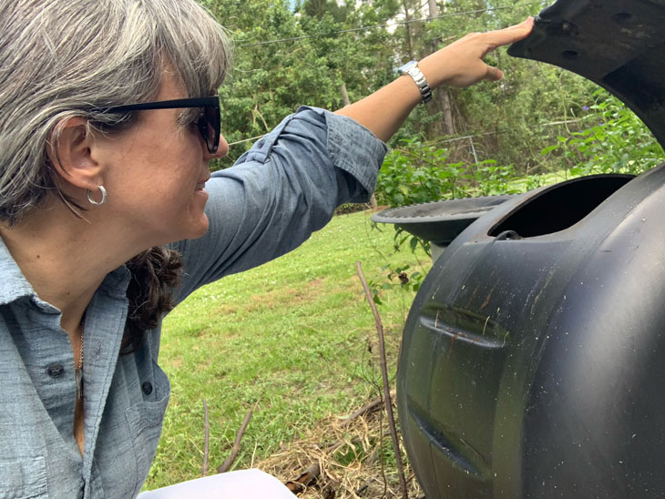 A homeowner checks her backyard composter.