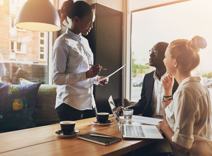 Two women and a man having a business meeting. Canva stock photo.