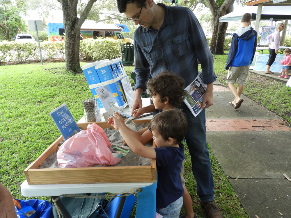 Two children and a man look at an environmental exhibit at Indian River Lagoon Day.