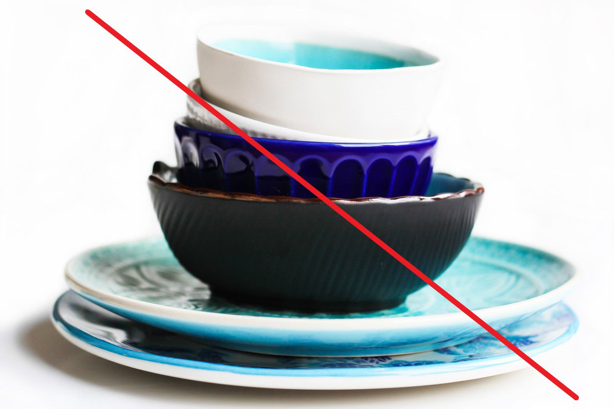 Small stack of ceramic plates and bowls with a red slash through the photo