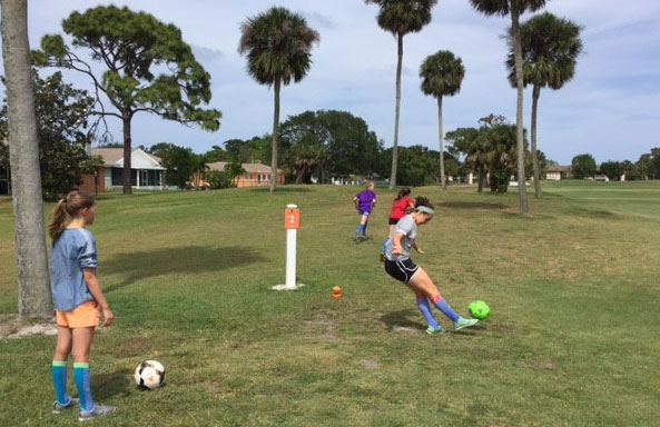 Two teen-age girls playing footgolf