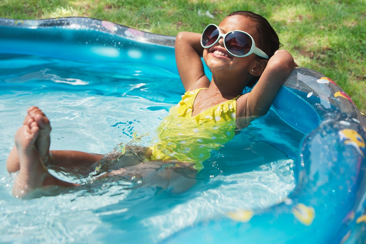 Young girl smiling and relaxed in a portable pool. Photo by Pool Safely/CPSC.