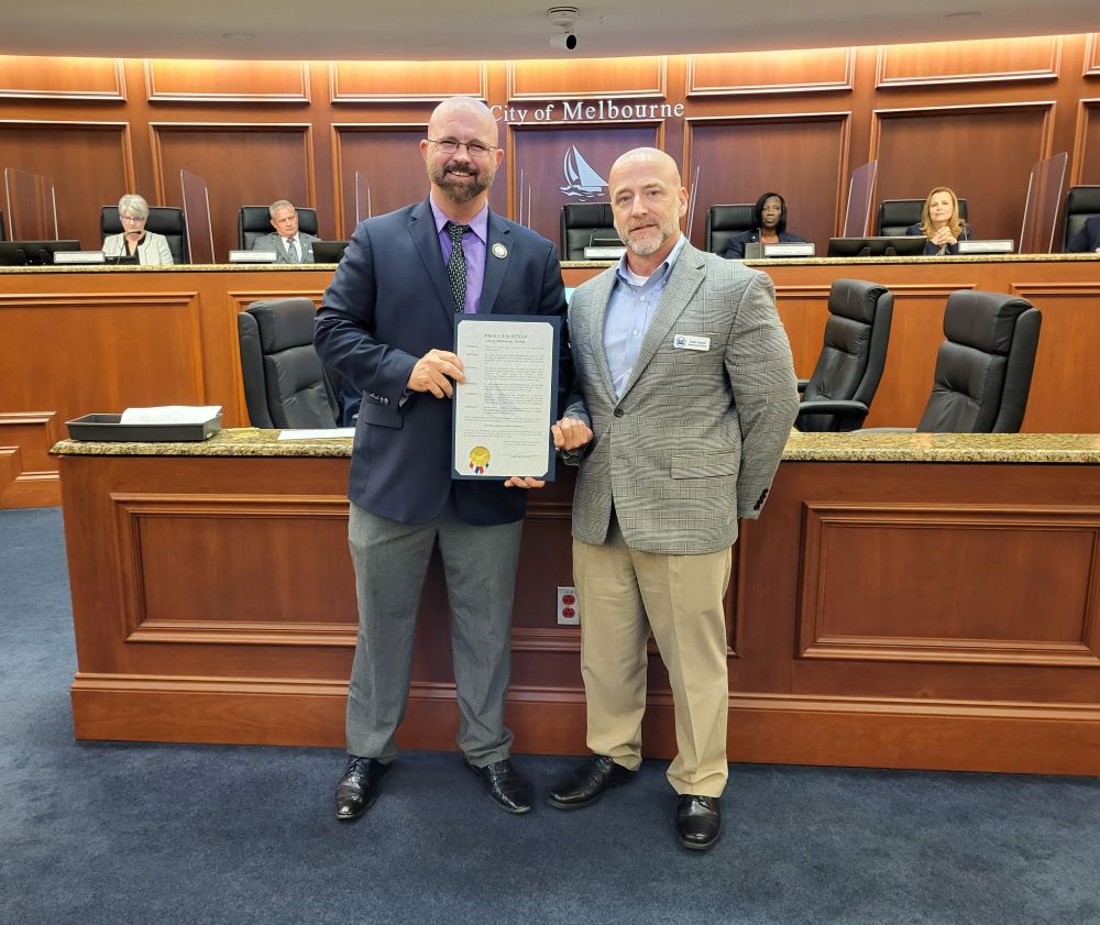 Mayor Alfrey holding proclamation and standing next to James Cannon in Council chamber