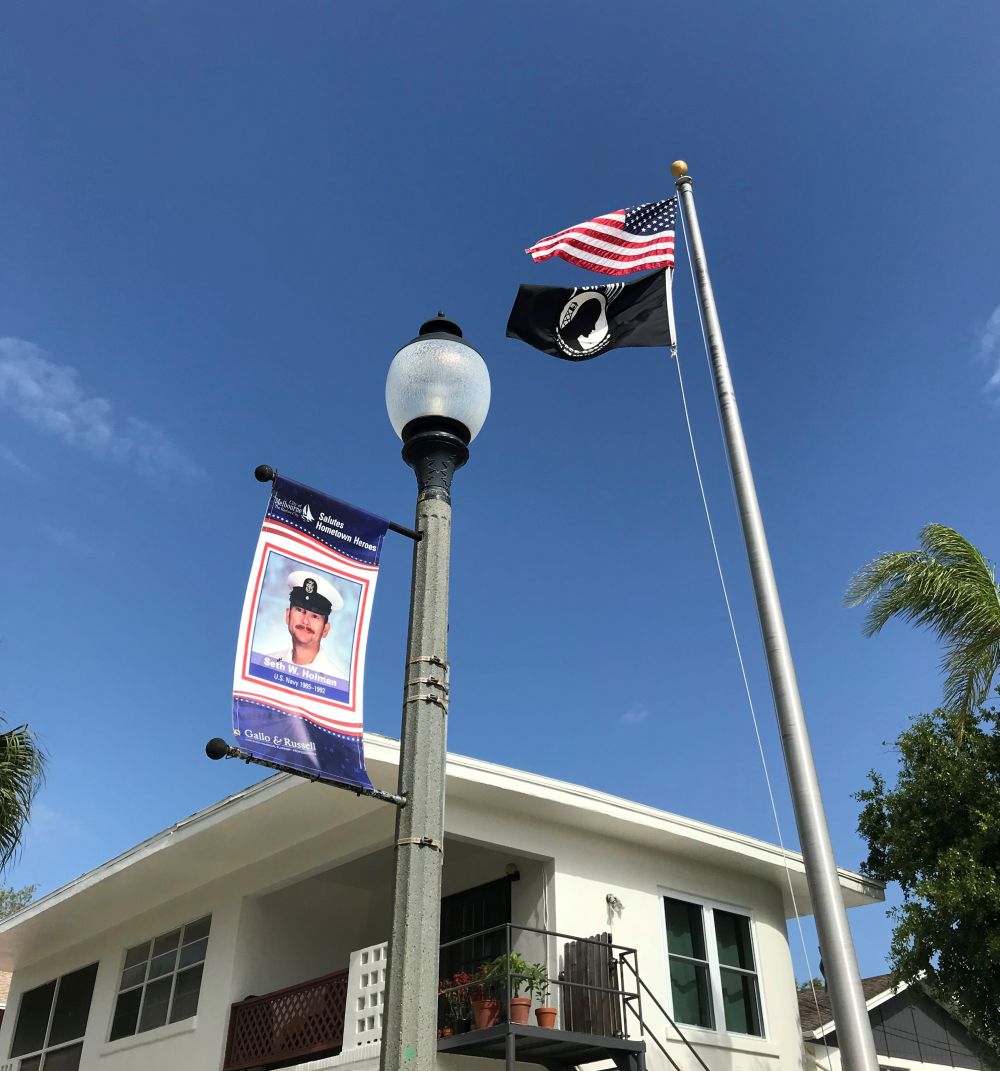 Street pole banner with text on the banner that says City of Melbourne Salutes Hometown Heroes, Seth W. Holman, U.S. Navy 1965-1992, and Gallo & Russell logo at the bottom.