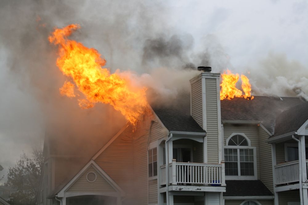 A portion of an apartment complex roof on fire. Photo by iStock.