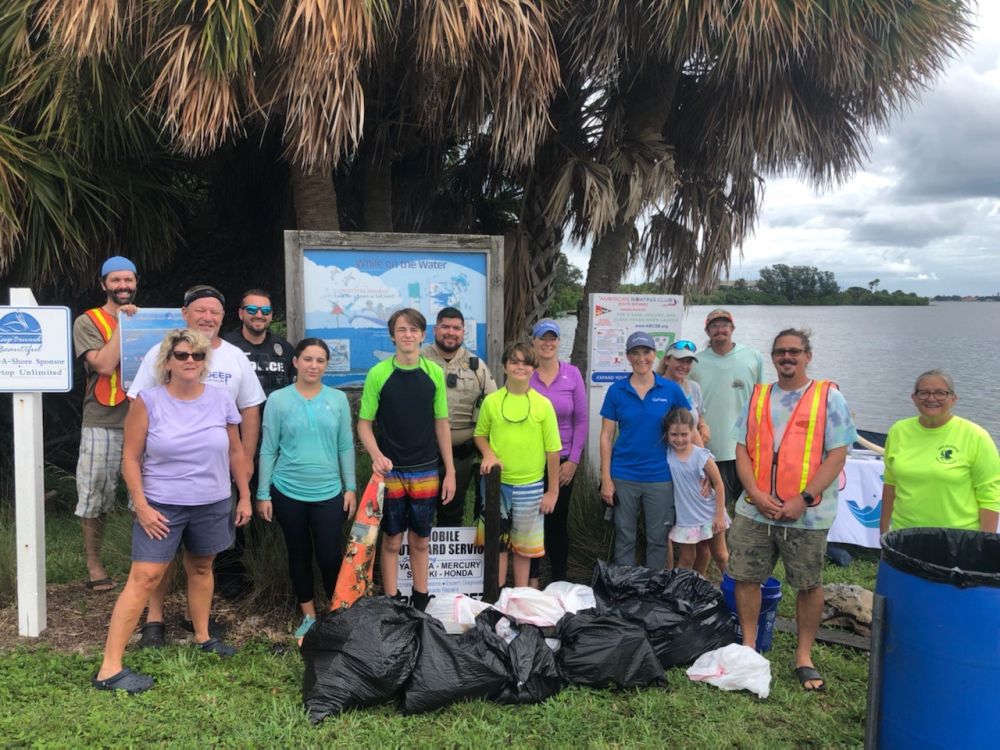 Group of volunteers standing in front of several bags of trash at Front Street Park.