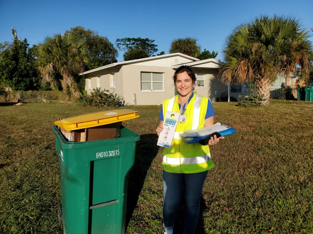 Megan Selva stands next to a recycling bin in front of a house.