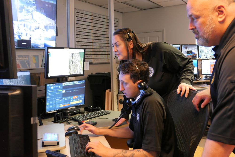 Three Communication Center employees looking at monitors