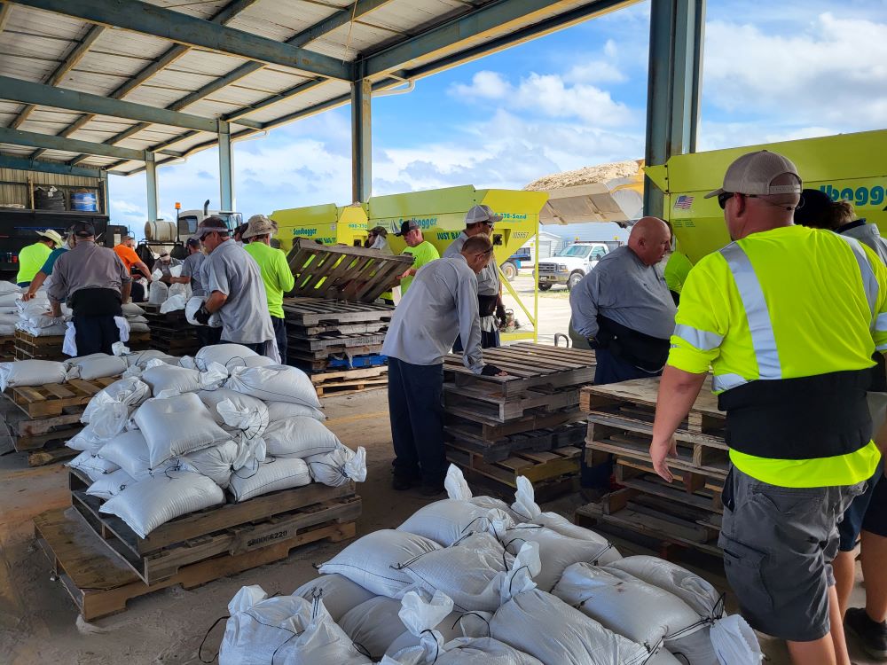 Pallets of sandbags and workers filling sandbags