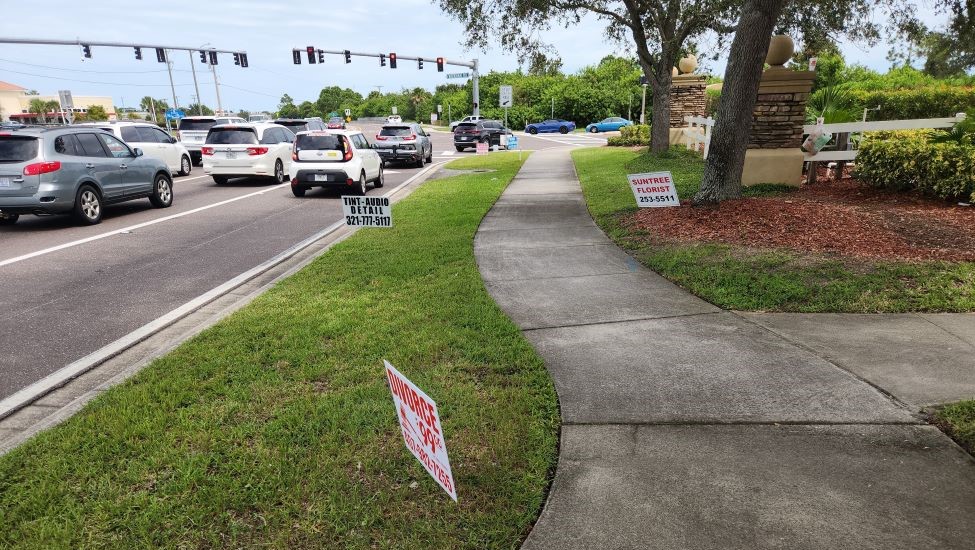 Three illegally placed temporary signs -- 2 in the right of way; one opposite the sidewalk.