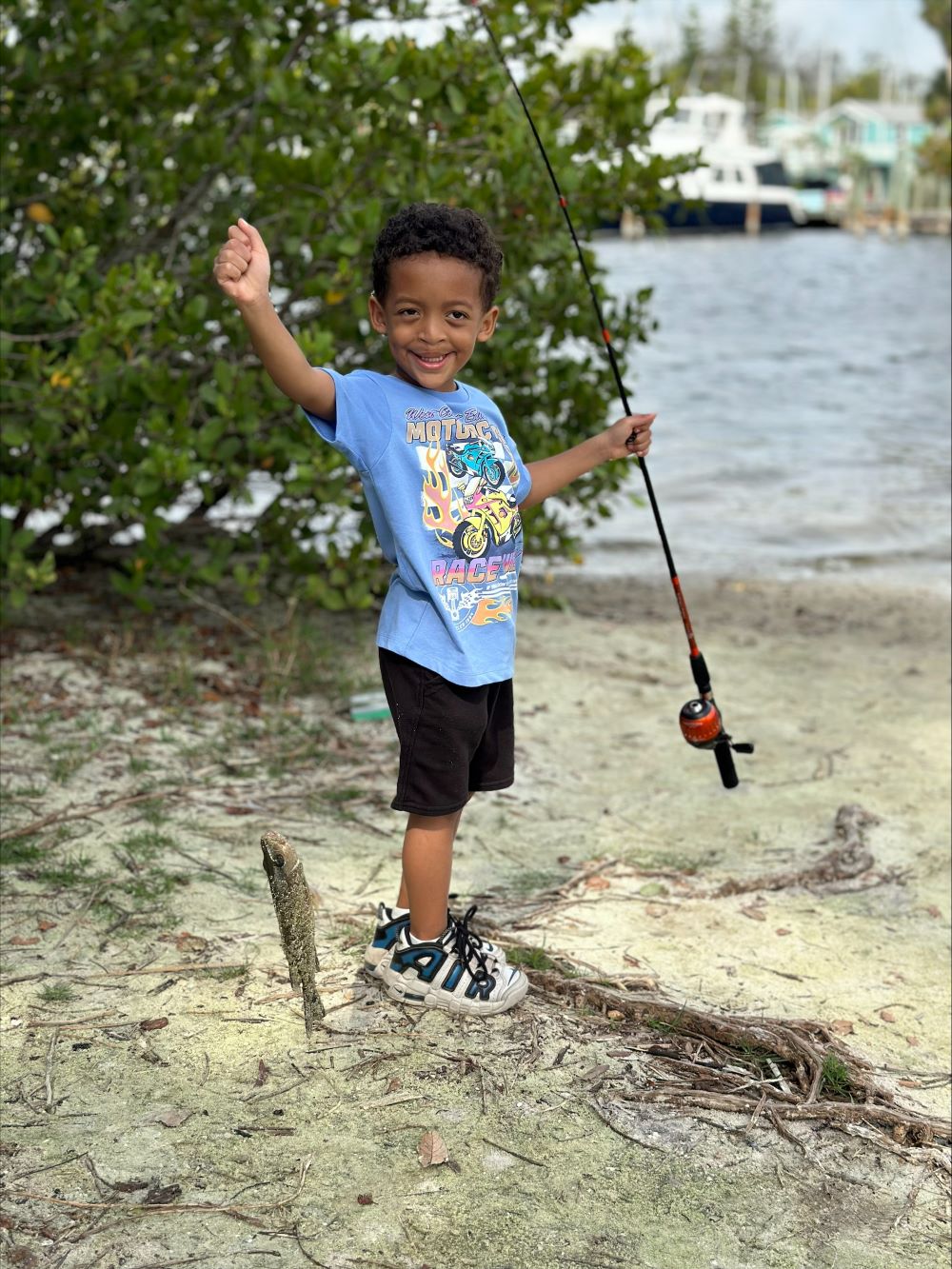 Smiling child holds a fishing pole and fish