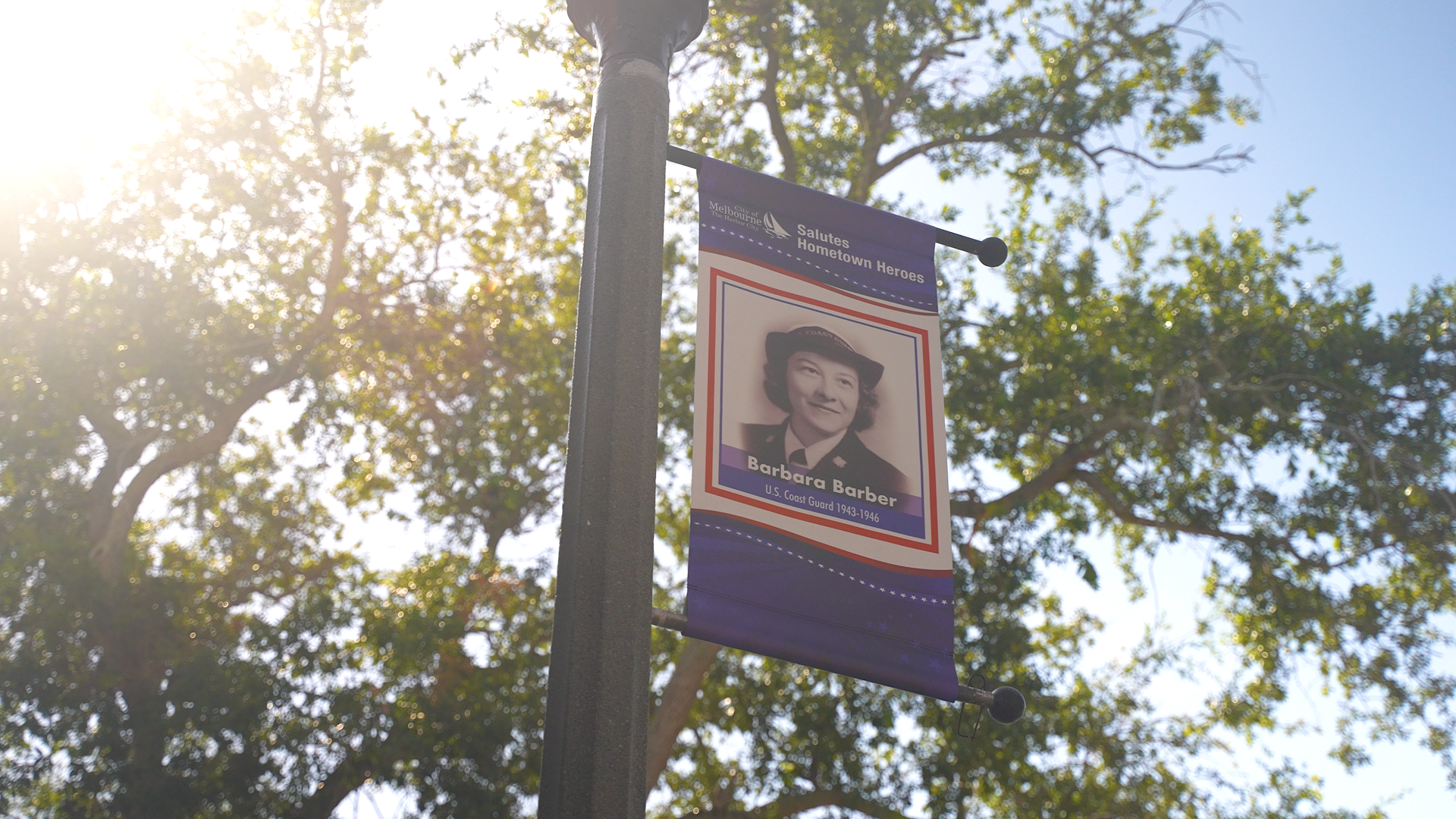 City of Melbourne Salutes Hometown Heroes banner on street pole next to a tree.