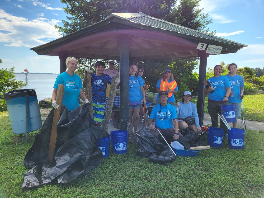 group of volunteers with trash bags and buckets under pavilion 