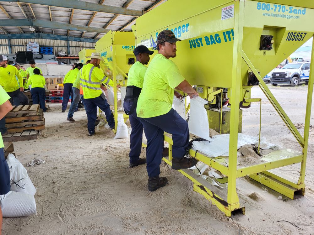 City employees filling sandbags using sandbagger machine